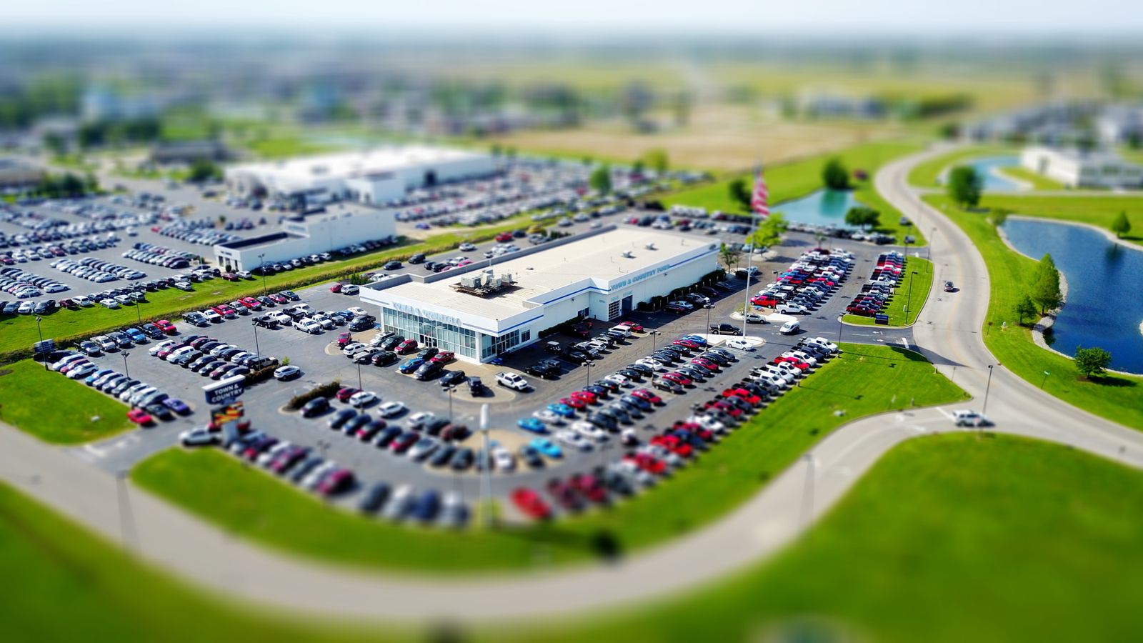 Aerial view of a large car dealership surrounded by rows of parked vehicles